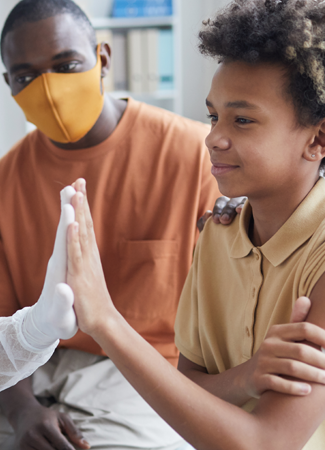 Health insurance in New Mexico photo of Black youth high fiving a health care worker